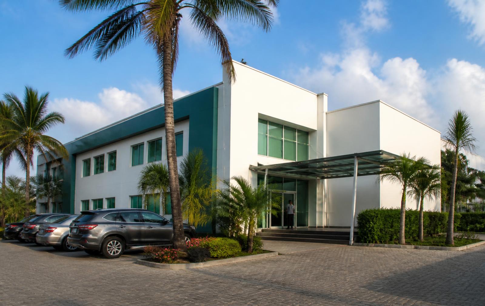 The Savannah Wellness Center building: a white and teal two-storey clinic with a glass entrance canopy and palm trees in the forecourt